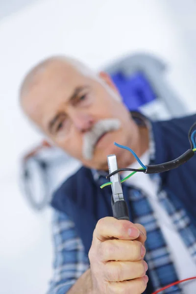 Senior-Elektriker hält Zange in der Hand und schneidet Elektrokabel — Stockfoto