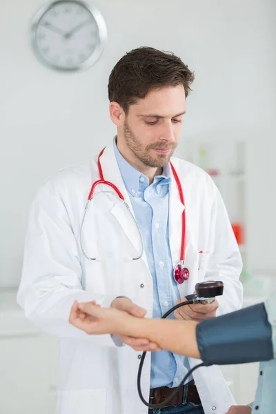 Portret van gelukkig arts controleren van patiënten bloeddruk in kliniek — Stockfoto