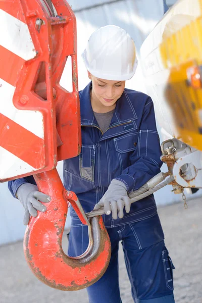 Vrouw verbonden metalen draad aan de haak van de kraan — Stockfoto