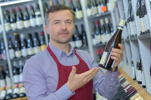 Portrait of sommelier with wine bottle in wine shop — Stock Photo, Image