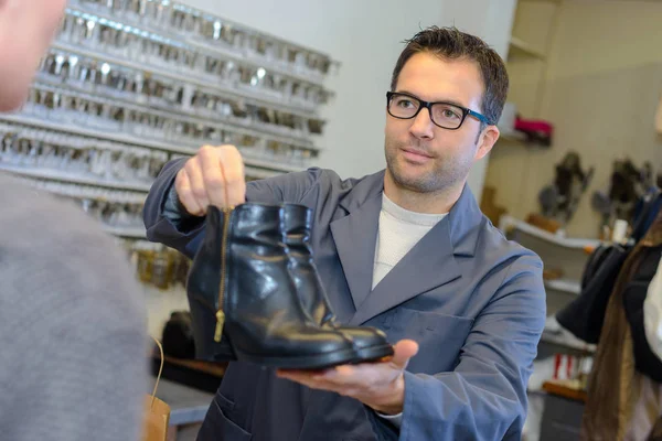 Cobbler handing boots back to customer