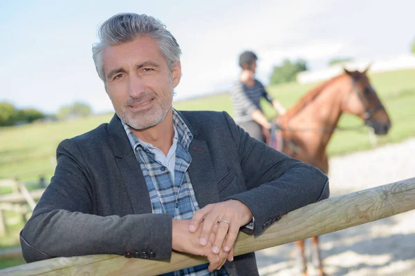 Man smiling with a rider behind him — Stock Photo, Image