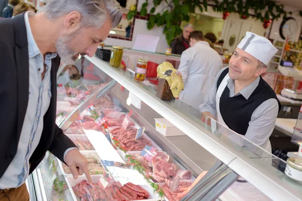 Mann wählt an Fleischtheke — Stockfoto