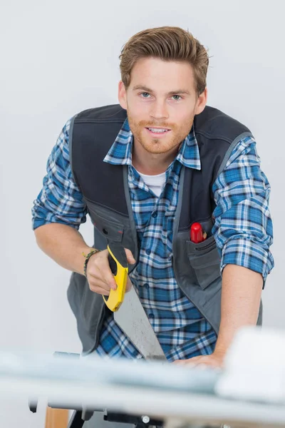 Retrato del carpintero que trabaja con una sierra en obra — Foto de Stock