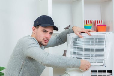 handsome technician installing air-conditioner in building clipart
