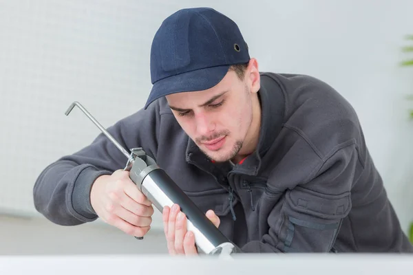 Concentré jeune technicien évier d'étanchéité dans la cuisine clients — Photo