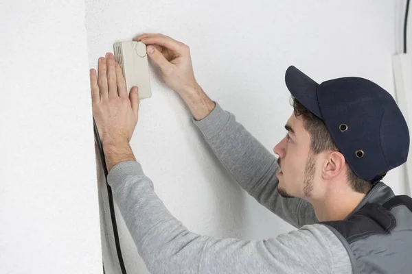 Pohledný mladý muž elektrikář instalace klimatizace v domě klienta — Stock fotografie