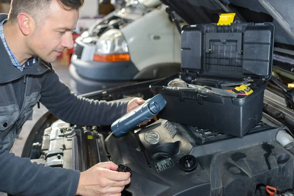 Mecánico de automóviles sustitución de aceite en el motor en el garaje — Foto de Stock