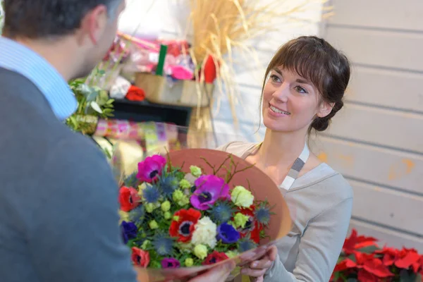 Blumenhändler reicht bunten Strauß an Kunden weiter — Stockfoto
