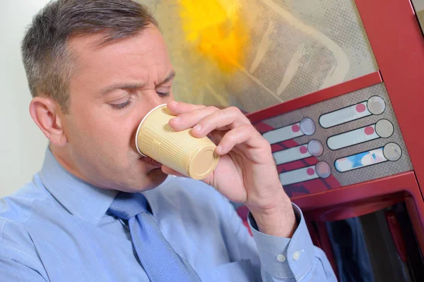 Человек пьет в автомате — стоковое фото