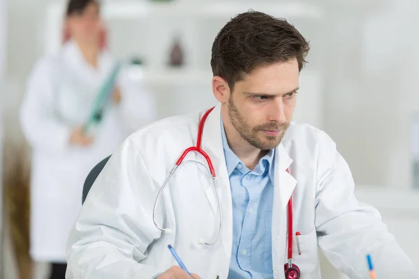 Schöner junger Arzt bei der Arbeit in seinem Büro — Stockfoto