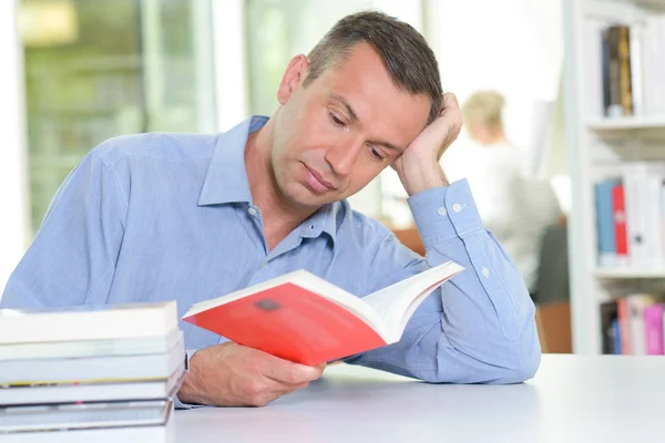 Man with head in hands reading — Stock Photo, Image