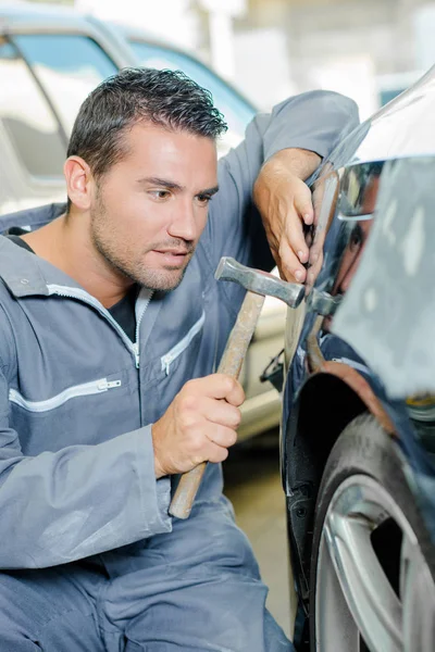 Man with hammer tapping car — Stock Photo, Image