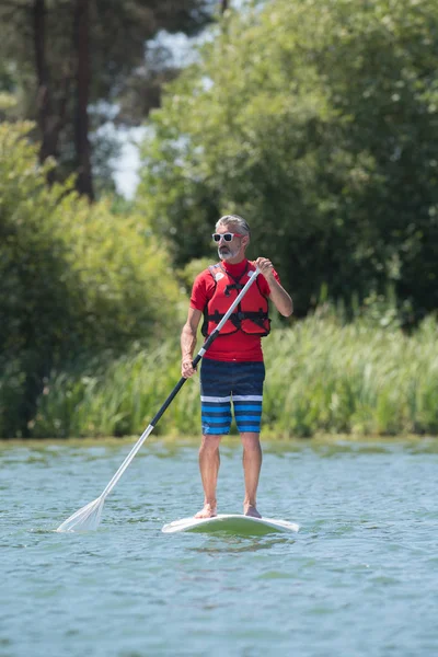 Uomo godendo di un giro sul lago con paddleboard — Foto Stock