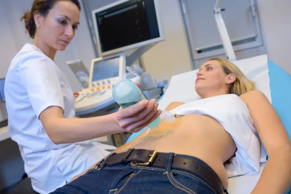 Enfermeira aplicando geléia no abdômen do paciente para ultra-som — Fotografia de Stock
