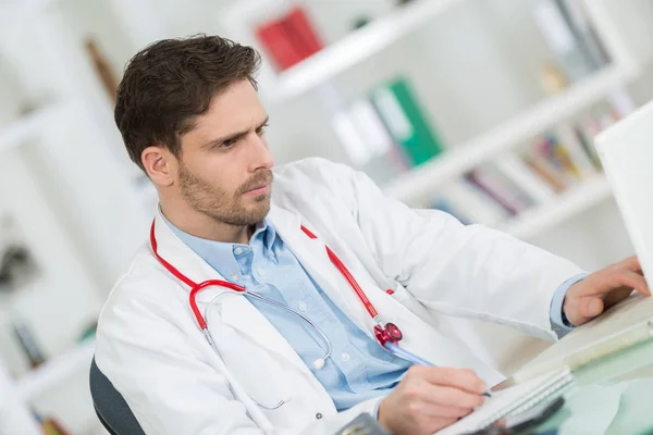 Medico maschio sorridente in cappotto bianco con computer — Foto Stock