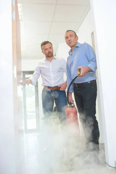 Hombres rociando extintor de incendios en la habitación —  Fotos de Stock