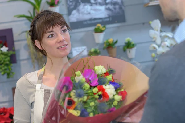 Florist passerar bukett blommor till klient — Stockfoto