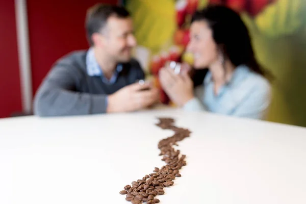 Sentier de grains de café menant à couple en arrière-plan — Photo