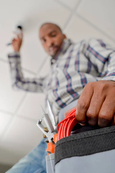 Constructeur travaillant sur le plafond, atteindre dans la ceinture d'outils — Photo