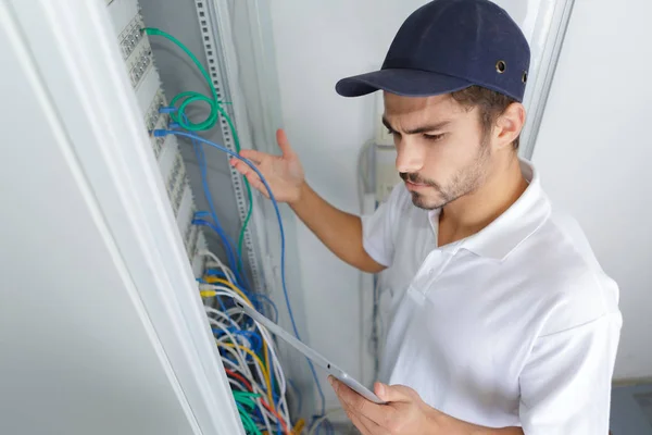 Electricista enfocado aplicando procedimiento de seguridad mientras trabaja en panel eléctrico —  Fotos de Stock