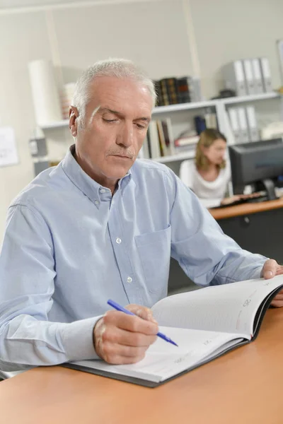 Senior office worker writing in his diary — Stock Photo, Image