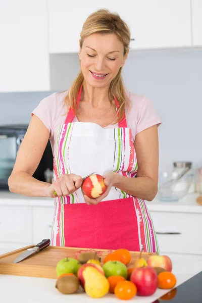 Donna anziana peeling mele nella sua cucina — Foto Stock