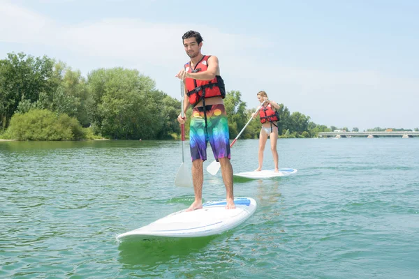 Silhueta de casal perfeito envolver stand-dup paddle embarque — Fotografia de Stock