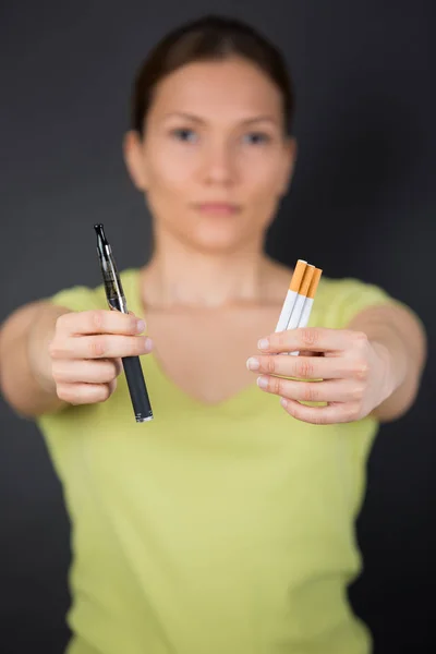 Mãos que oferecem em troca cigarros normais e um cigarro eletrônico — Fotografia de Stock