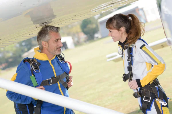 Manliga och kvinnliga fallskärmshoppare under vingen av flygplan — Stockfoto