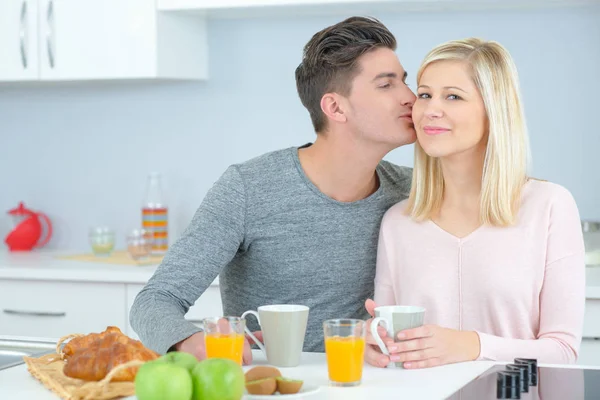 Mann küsst Partnerin am Frühstückstisch — Stockfoto