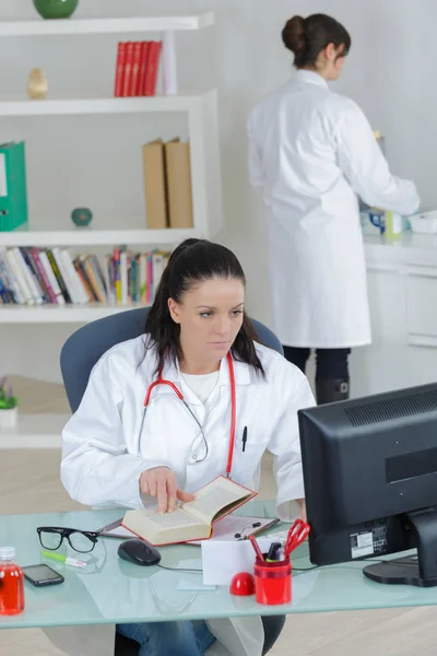 Médico que trabaja en la oficina con la enfermera en segundo plano — Foto de Stock