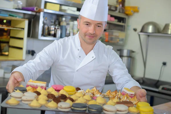 Pastry chef holding delicious looking cakes and pastries — Stock Photo, Image