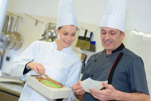 Pâtissier et assistant préparant le gâteau — Photo