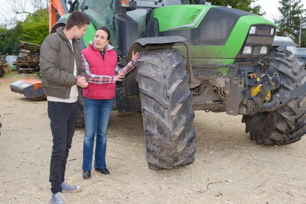 Yeni çiftçiye yeni traktör satan çekici bir kadın. — Stok fotoğraf