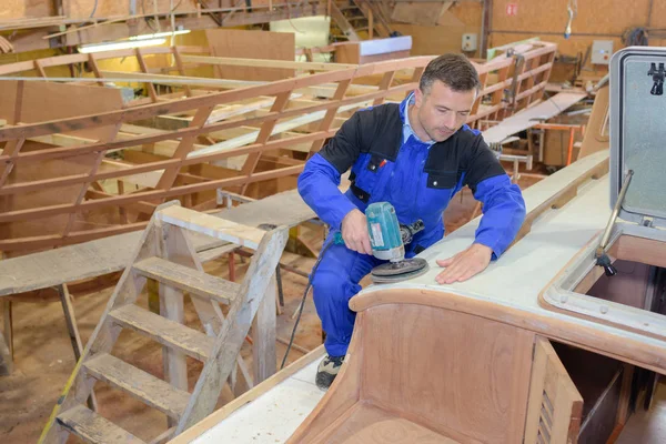 Člověk pomocí brusky na dřevěné lodi — Stock fotografie