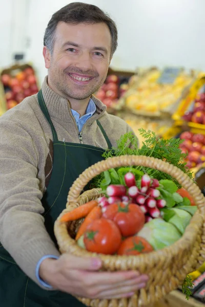 Greegrocer presenting basket of produce — Stock Photo, Image