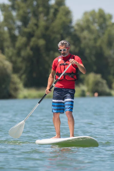 Człowiek cieszyć jazdą na jeziorze z paddleboard — Zdjęcie stockowe