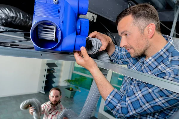 Man aan het werk op een ventilatie box — Stockfoto