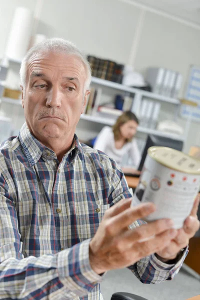 Homem confuso segurando uma lata de tinta — Fotografia de Stock