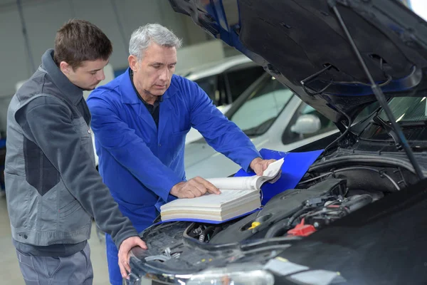 Automechanik učitel a praktikant provádějící zkoušky na mechanické škole — Stock fotografie