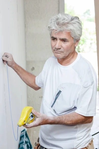 Builder taking measurement of wall — Stock Photo, Image