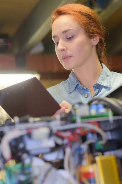 複雑な電気システムによってクリップボードを持つ女性 — ストック写真