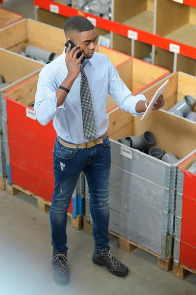 Trabalhador na loja de suprimentos de canalização, usando telefone — Fotografia de Stock