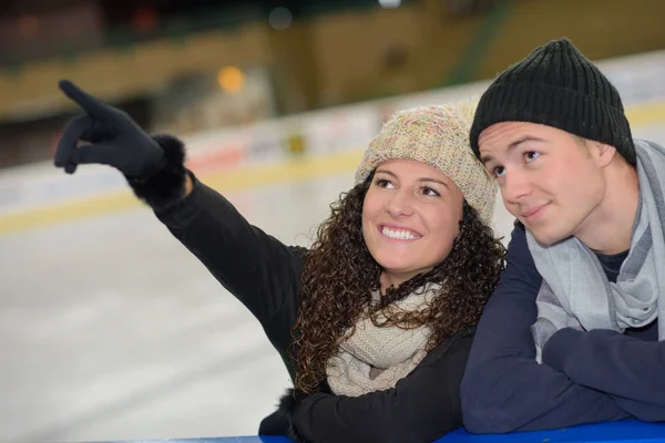 Jeune couple à la patinoire pointant vers le haut — Photo