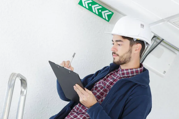 Inspector en escritura hardhat en portapapeles — Foto de Stock