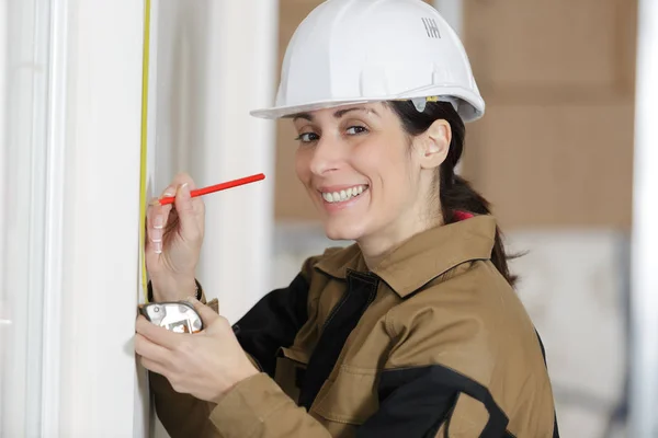 Constructora femenina adulta mostrando asistente midiendo la pared —  Fotos de Stock