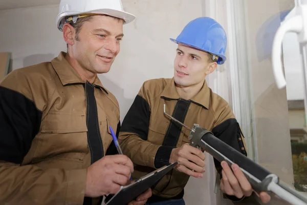 Trabalhador da construção civil aprendendo a instalar janela em casa — Fotografia de Stock