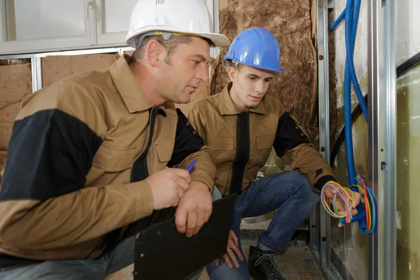 Dois trabalhadores construtor eletricista instalando cabo industrial — Fotografia de Stock