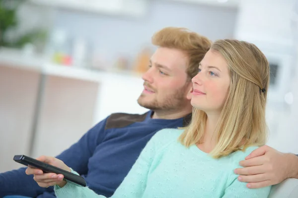 Embracing couple using remote control — Stock Photo, Image